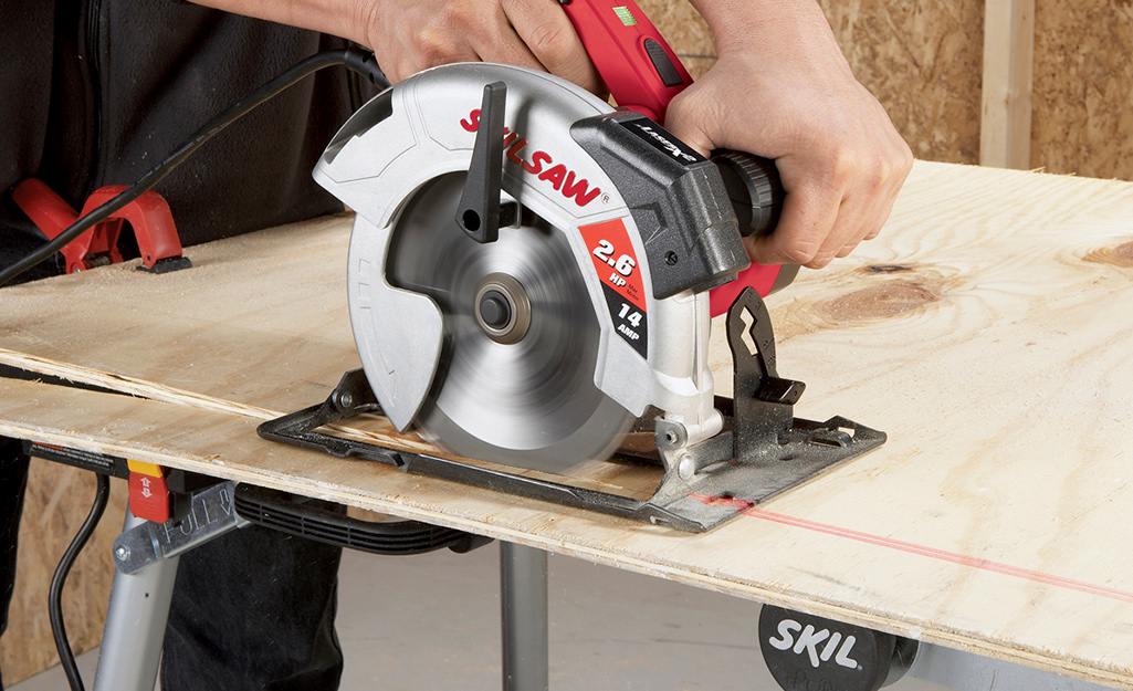 A person using a saw to cut a thin piece of plywood. A person using a saw to cut a thin piece of plywood.