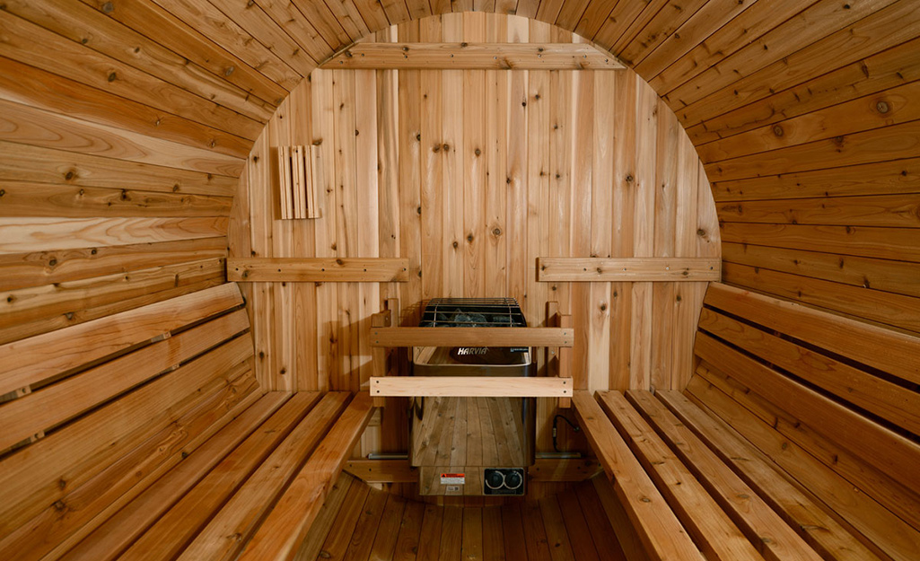 Wooden benches fit perfectly against the rounded walls of a barrel-shaped cedar home sauna.