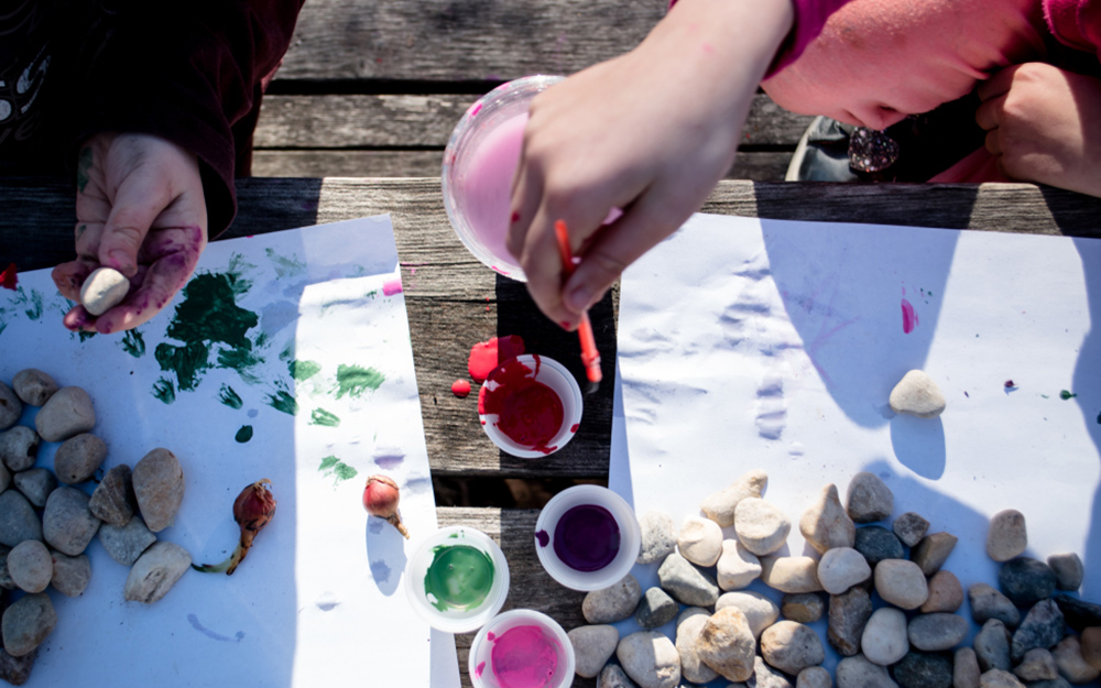 People painting small rocks for decoration.