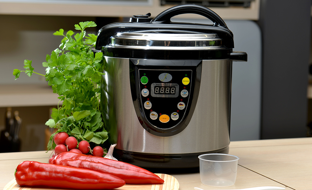 A pressure cook on a counter top with vegetables. A pressure cook on a counter top with vegetables.