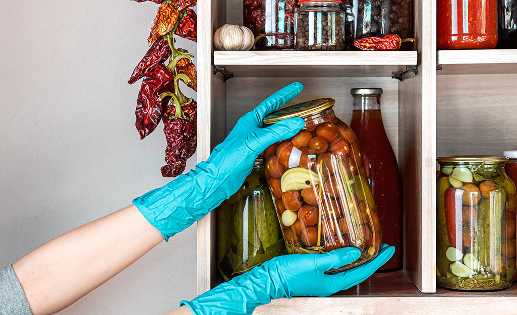 A person wearing gloves and storing food in a pantry. A person wearing gloves and storing food in a pantry.