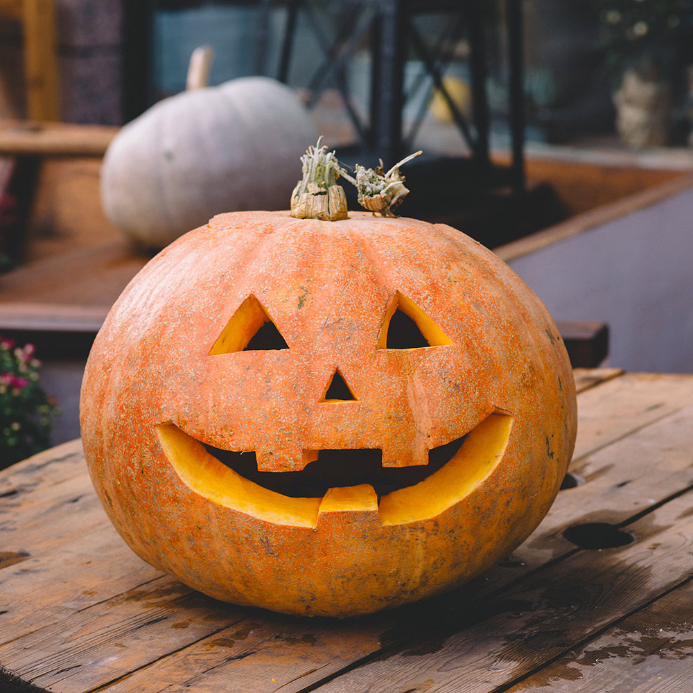 A freshly carved pumpkin sits on an outdoor table. 