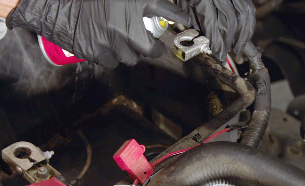 A person cleans a car battery's terminals. 