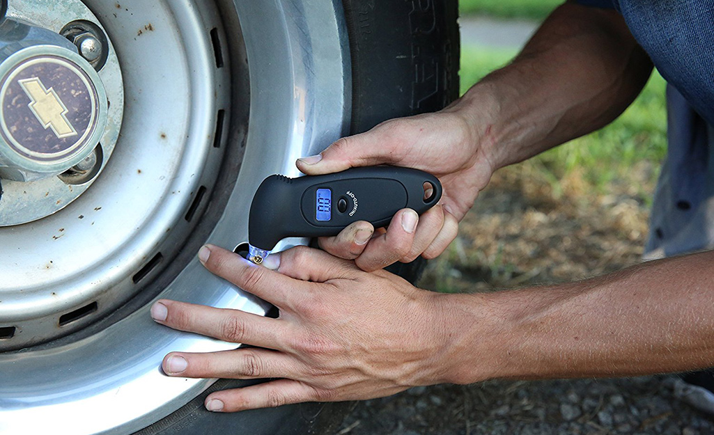 A person uses a gauge to test a tire's air pressure.