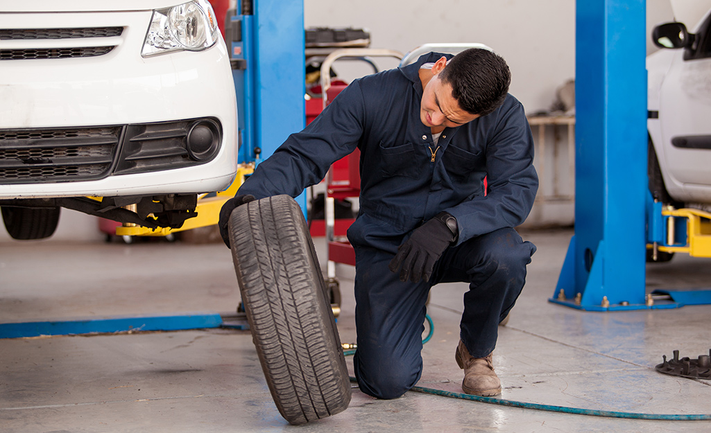 A mechanic at an auto shop checks out a tire in need of repair.