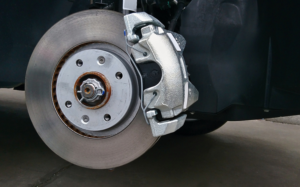 A caliper rests on a brake rotor before an adjustment.