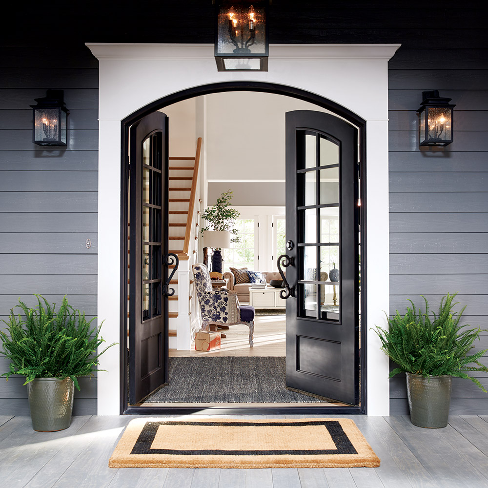 Two black lantern-style outdoor sconces and a matching overhead light frame the entrance of a home.