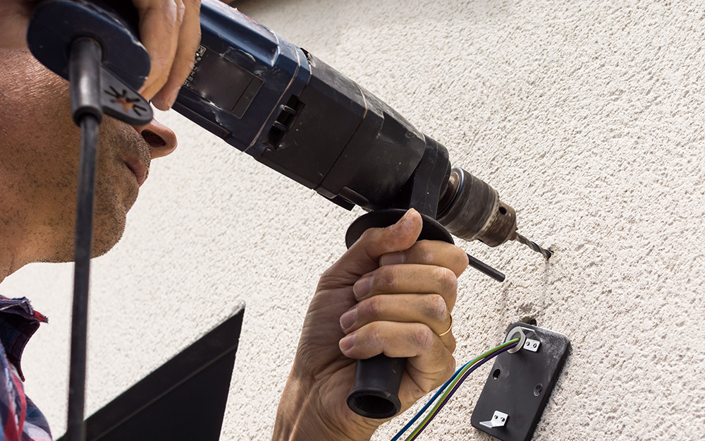 A man screwing holes into the exterior of a home