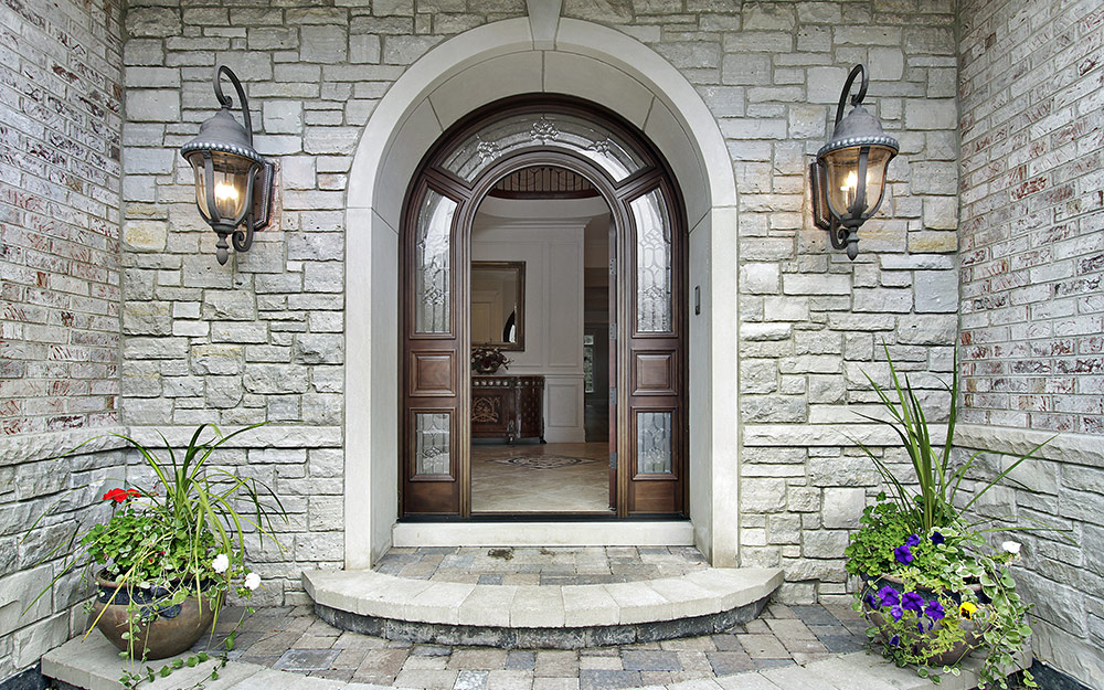 A stone exterior of a home with mounted lanterns