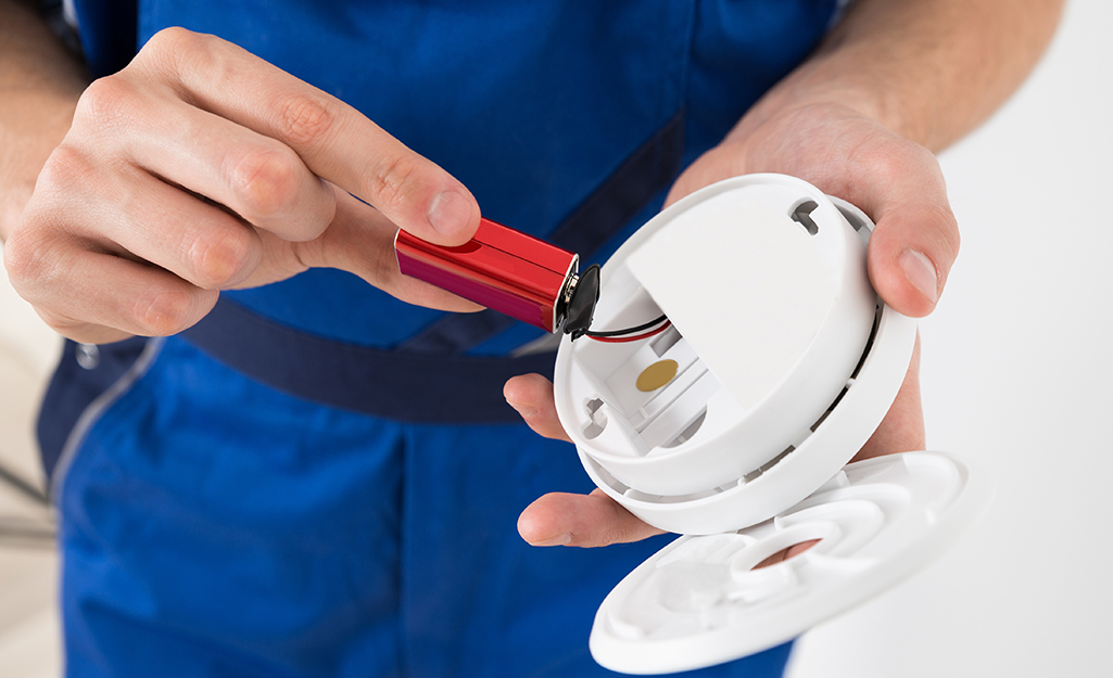 Someone replacing a battery in a smoke alarm.