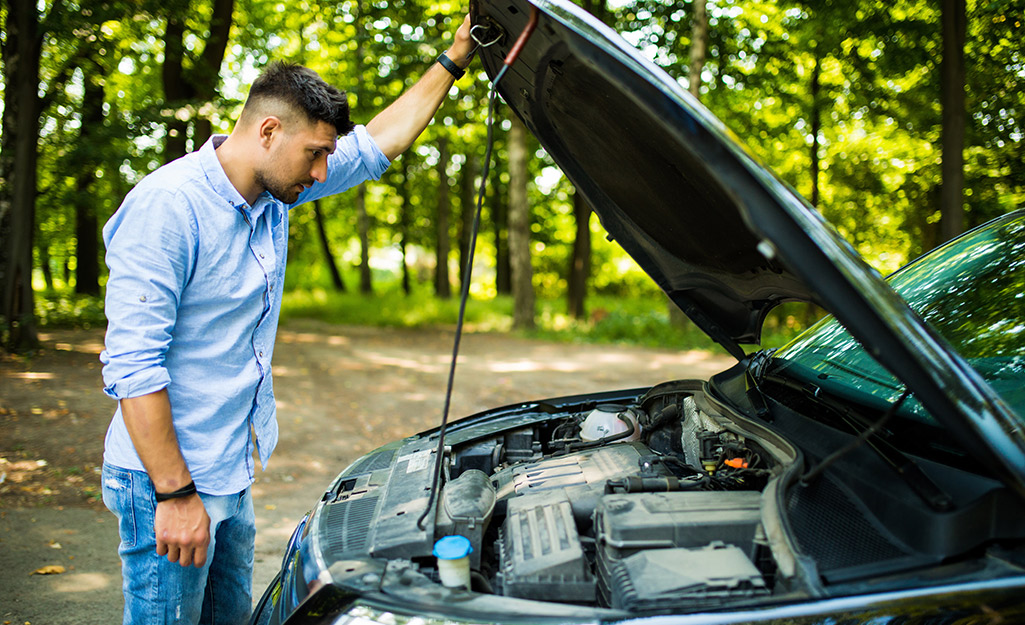 A man opening the hood of a car.