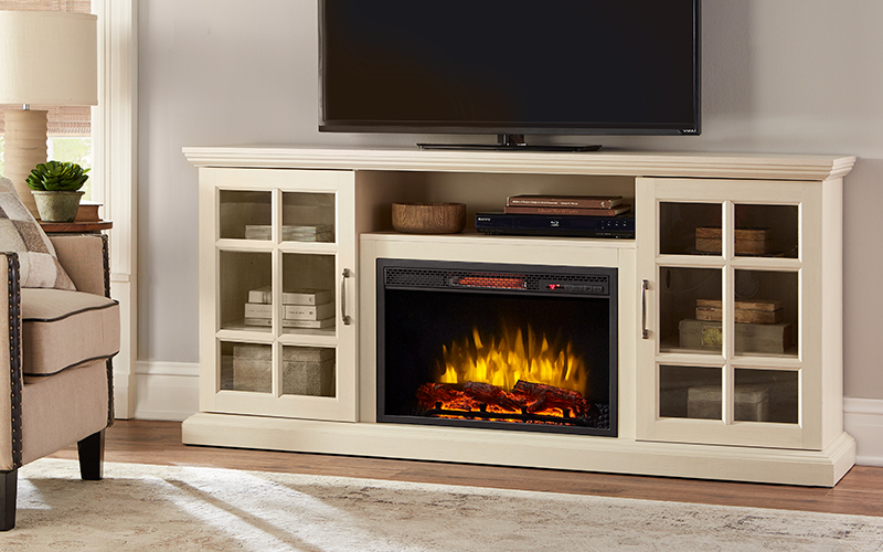 An electric fire place glows in a beige TV stand with two doors.