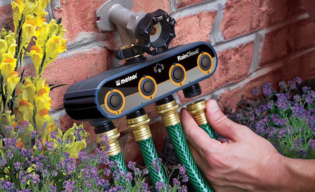 A person connecting a hose to an irrigation timer.