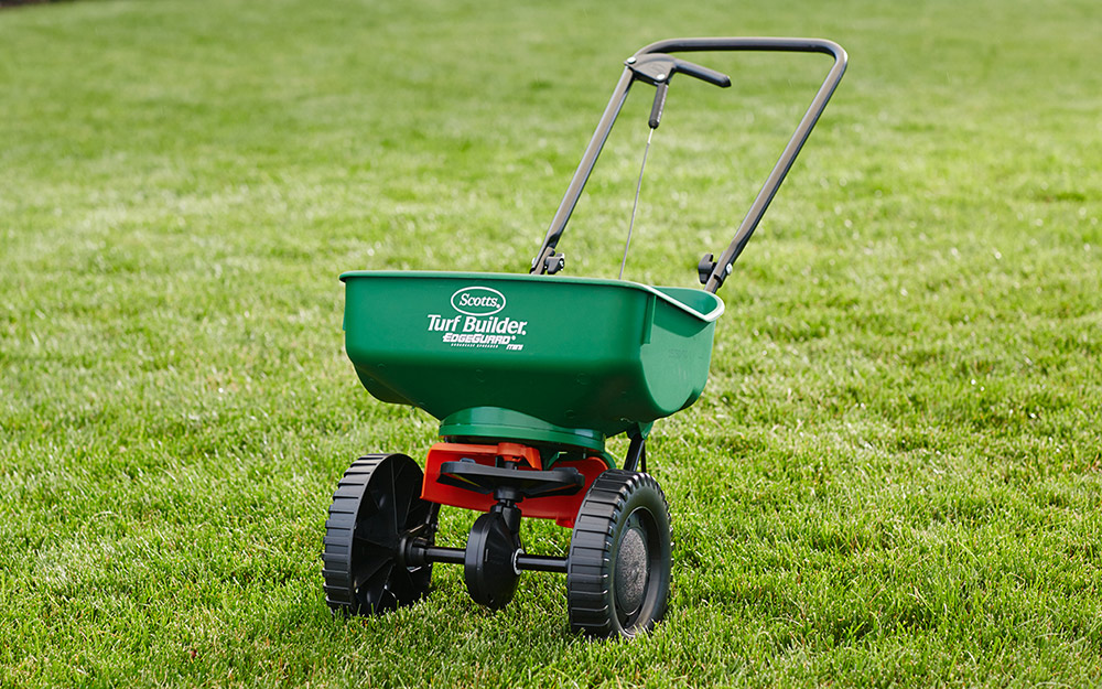 Fertilizer spreader sitting on a lawn.