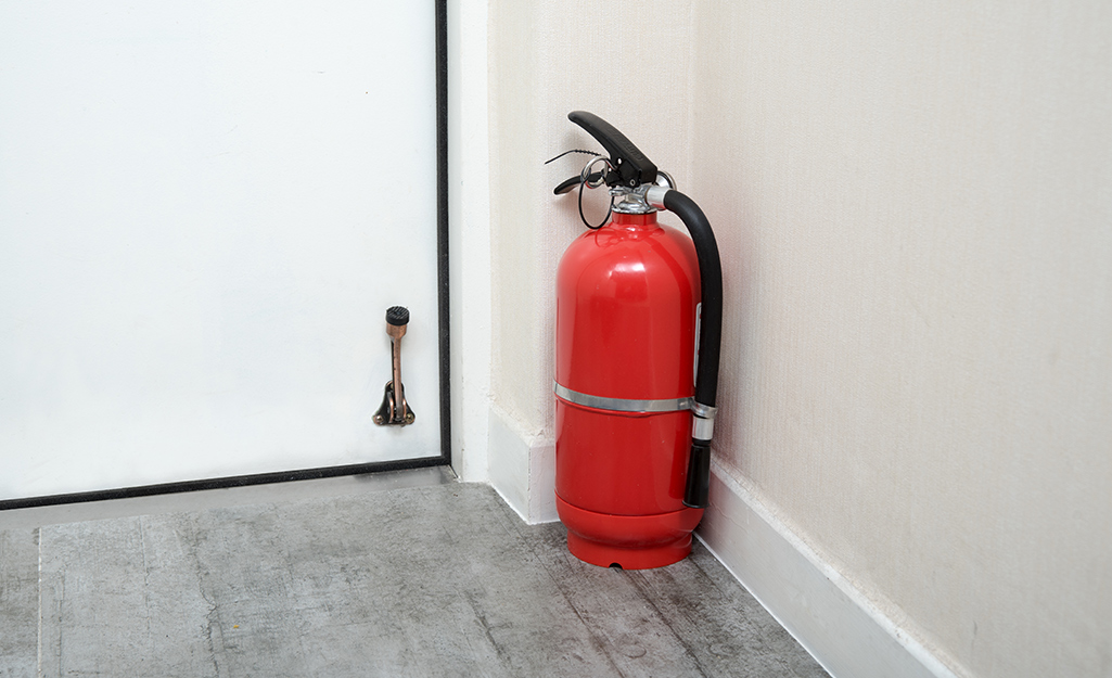 A fire extinguisher placed on the floor next to a doorway.