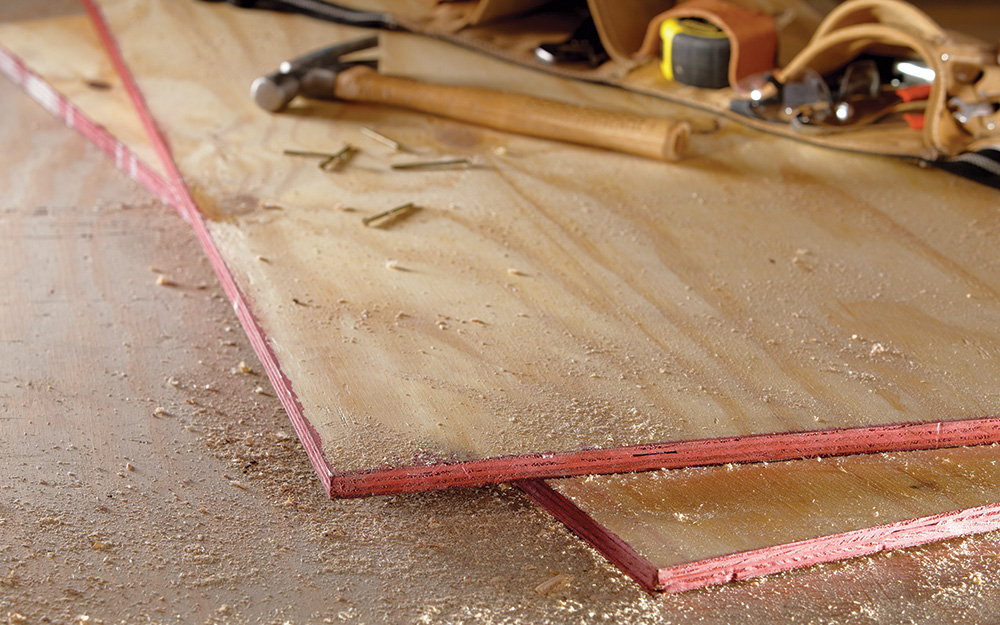 Two sheets of plywood lying on a concrete floor.