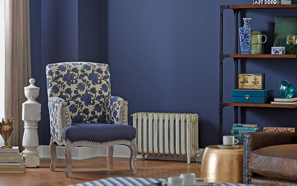 A blue and white floral print chair against a dark blue satin finish wall.