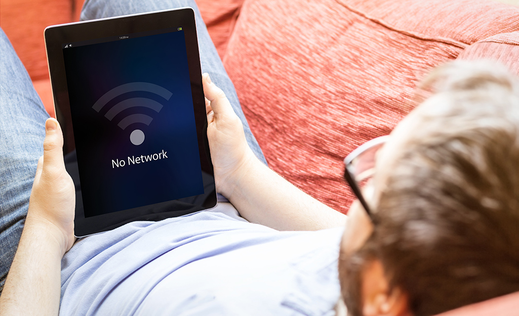 Man lying on couch with tablet that shows there's no WiFi in his room. Man lying on couch with tablet that shows there's no WiFi in his room.