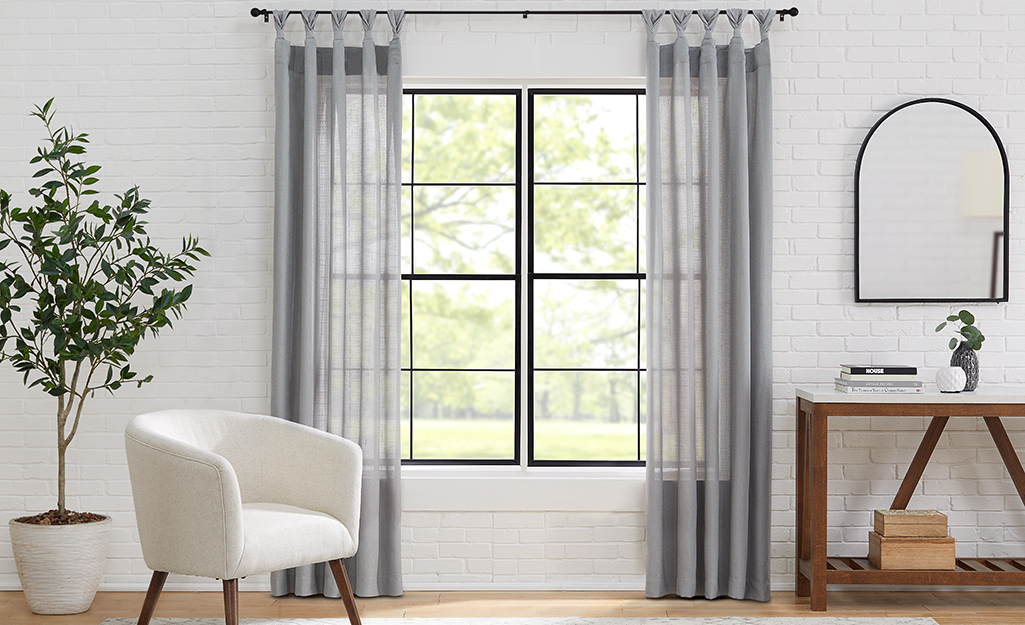 A living room area with sheer grey curtains.