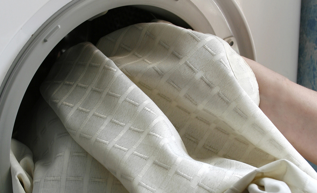 Curtains being placed in a washing machine. 