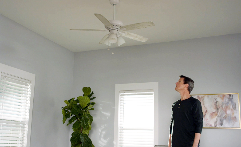 A person checks the turning direction of a ceiling fan.