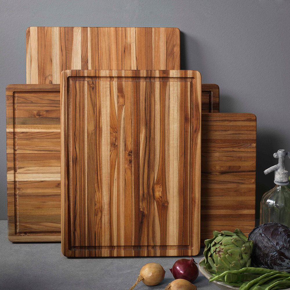 Wooden cutting boards lean against a wall next to an arrangement of vegetables.