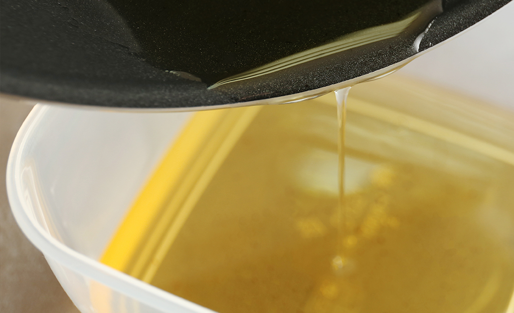 Oil is poured out of a fryer into a bowl.