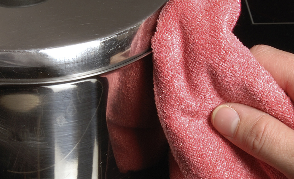 A person uses a cloth to wipe the outside of a deep fryer