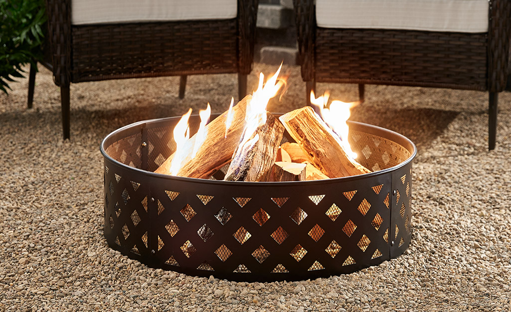 A fire burns in a metal fire pit that has a lattice work pattern.