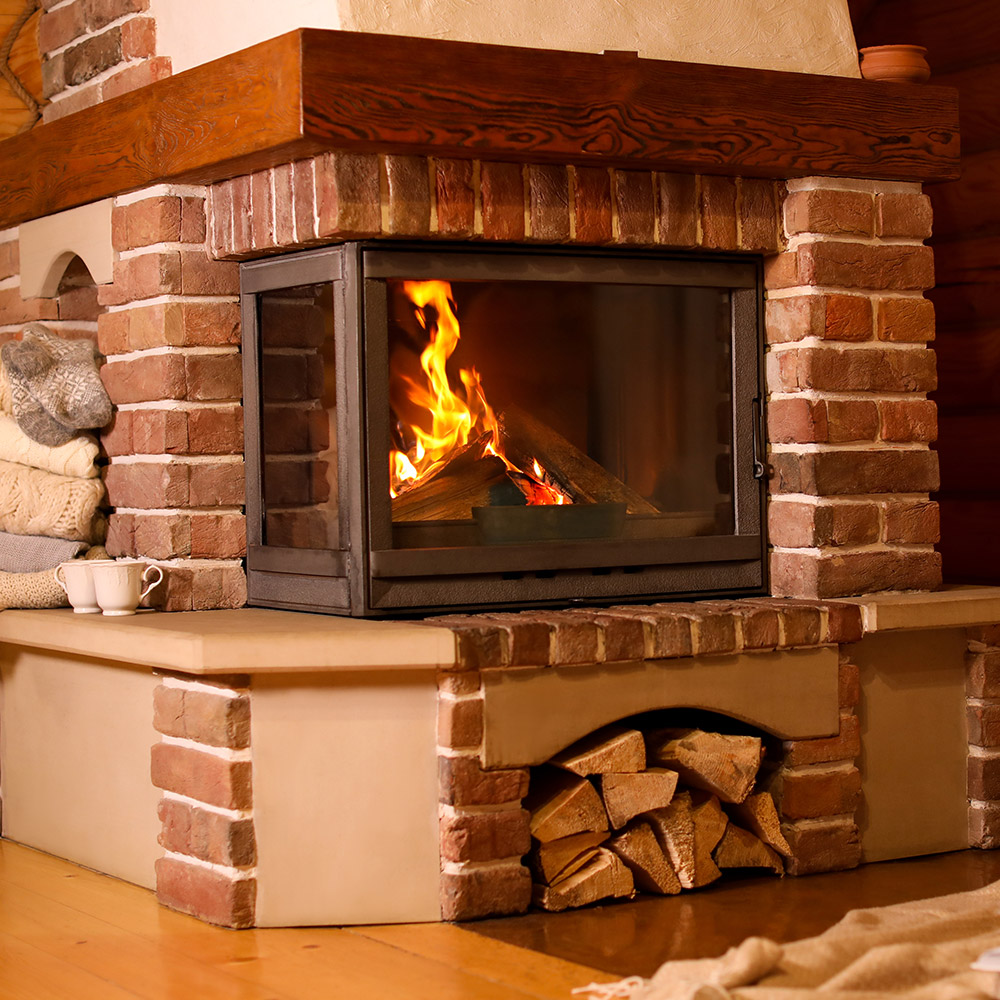 A fire burns in a brick fireplace in a room with hardwood floors.