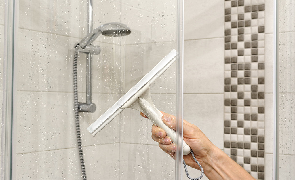 A squeegee is used to clean a glass shower door