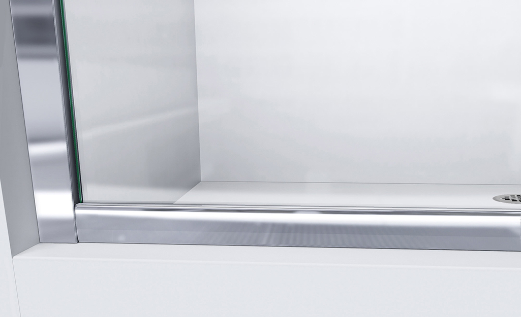 A clean glass shower door sits inside of a shiny metal door track