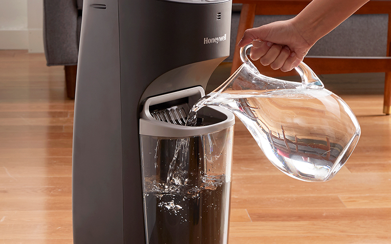 A person filling the water tank of a humidifier.