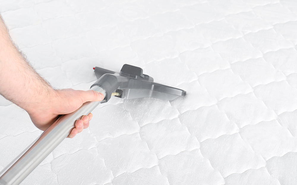 A person cleaning a mattress by vacuuming. 