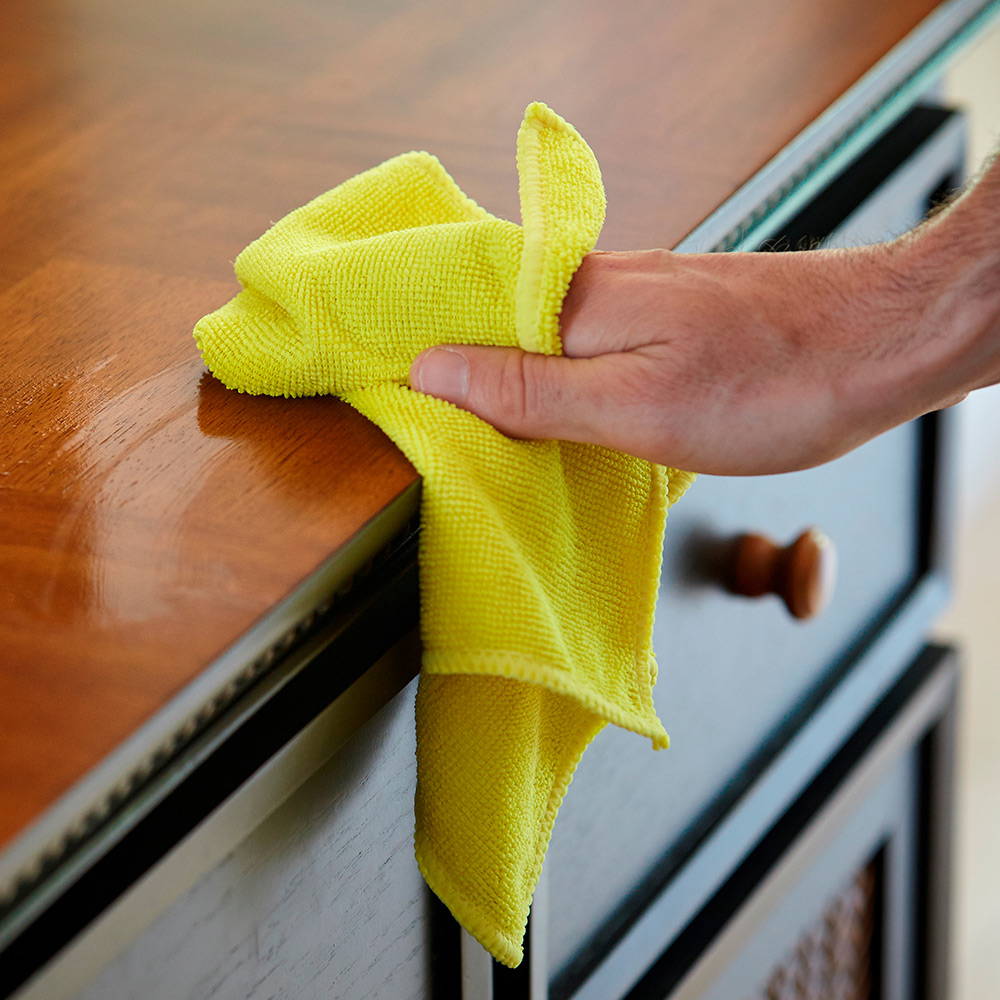 A person cleaning a counter with a microfiber cloth.