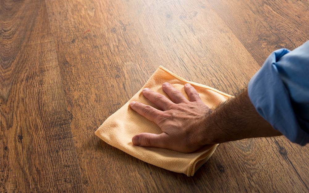 A person wiping a table with a microfiber cloth.