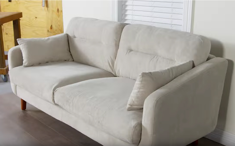 A light beige couch of microfiber material in a living space.
