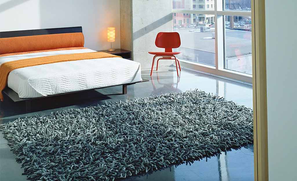 A thick shag rug placed at the foot of a bed.