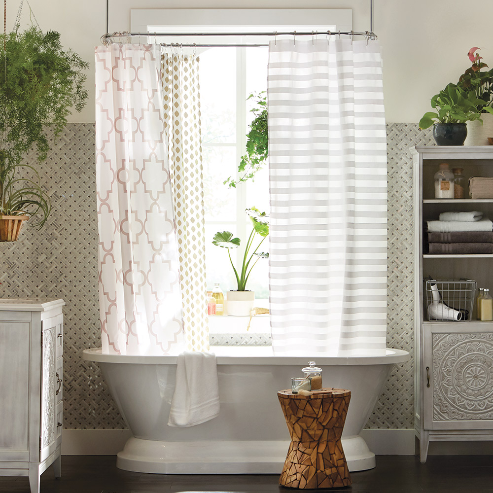 White patterned shower curtains hang in a bathtub shower in a white bathroom.
