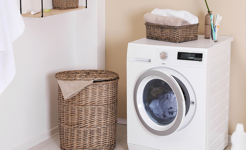 A white washing machine contains a load of white laundry in a laundry room.