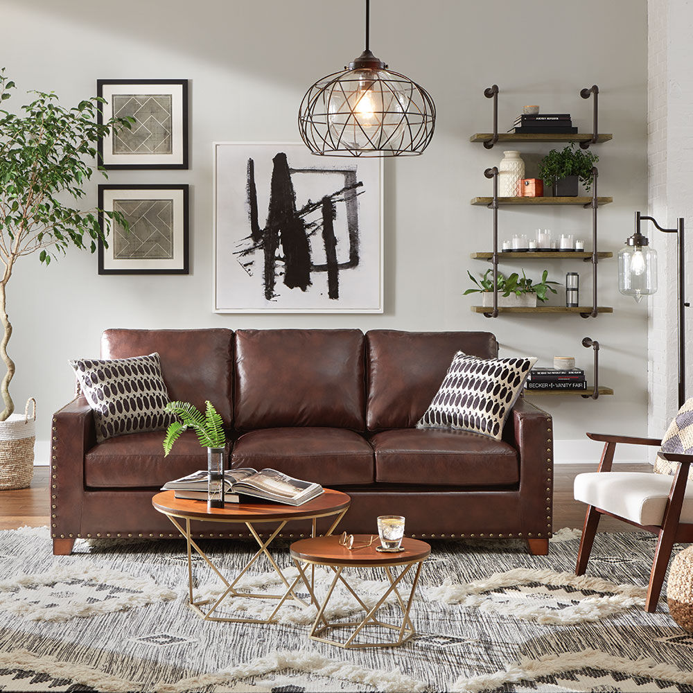 A brown leather sofa in a room with a wool area rug.