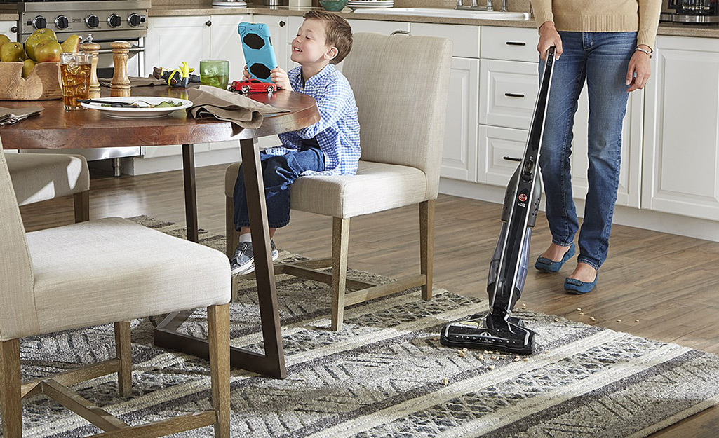 A person vacuuming a wool rug.