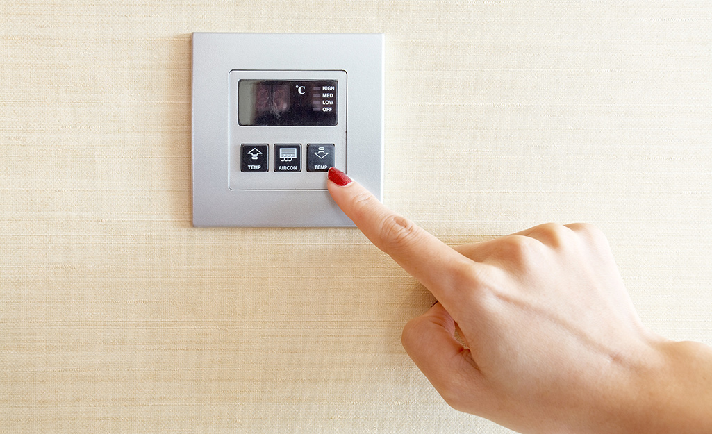 A woman presses a button to shut off an A/C unit.