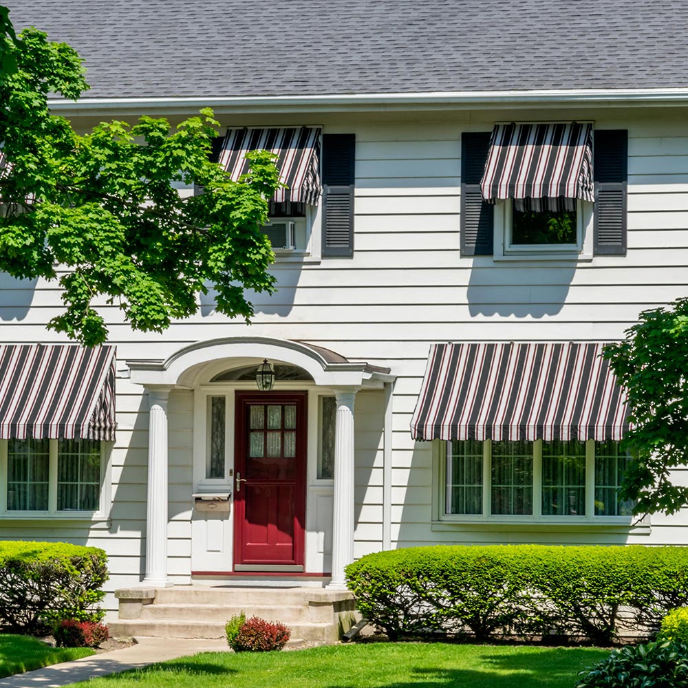 Red, white and blue awnings installed on a white two-story home.