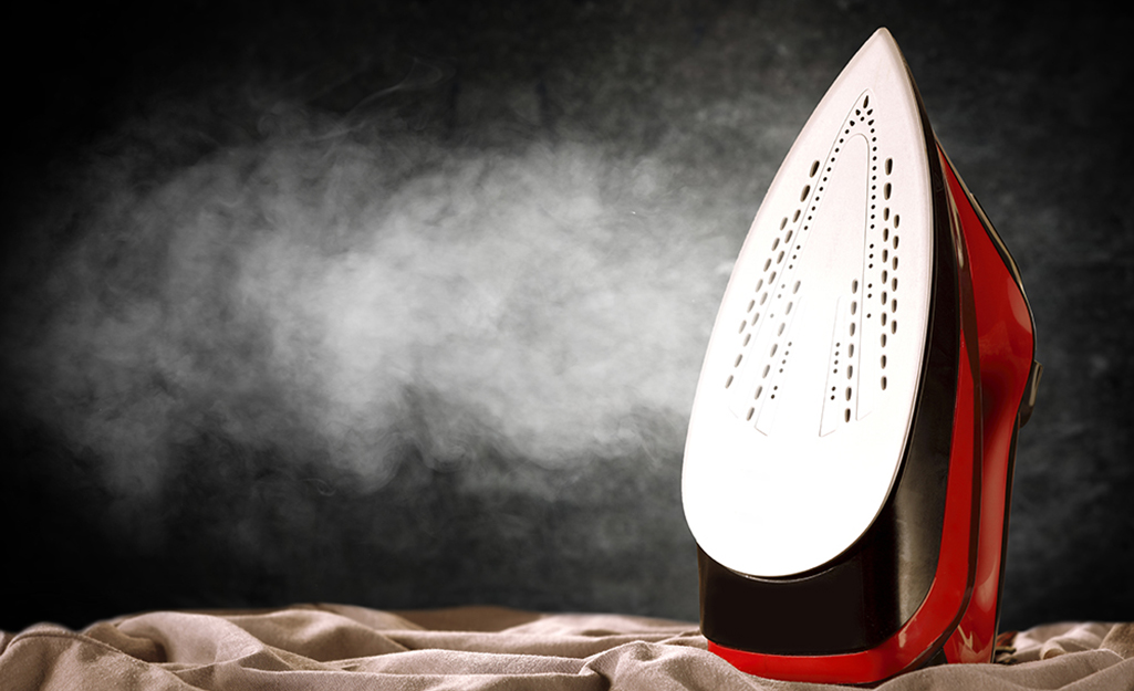 An iron with a clean soleplate releases a cloud of steam.