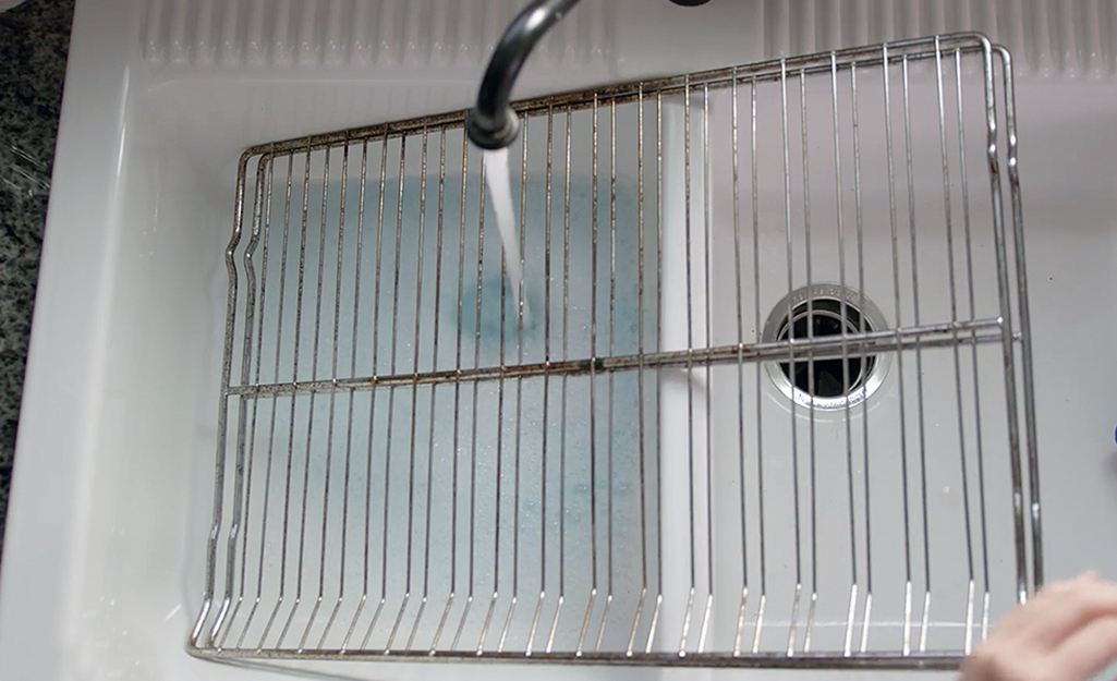 Someone cleaning oven racks in a sink.