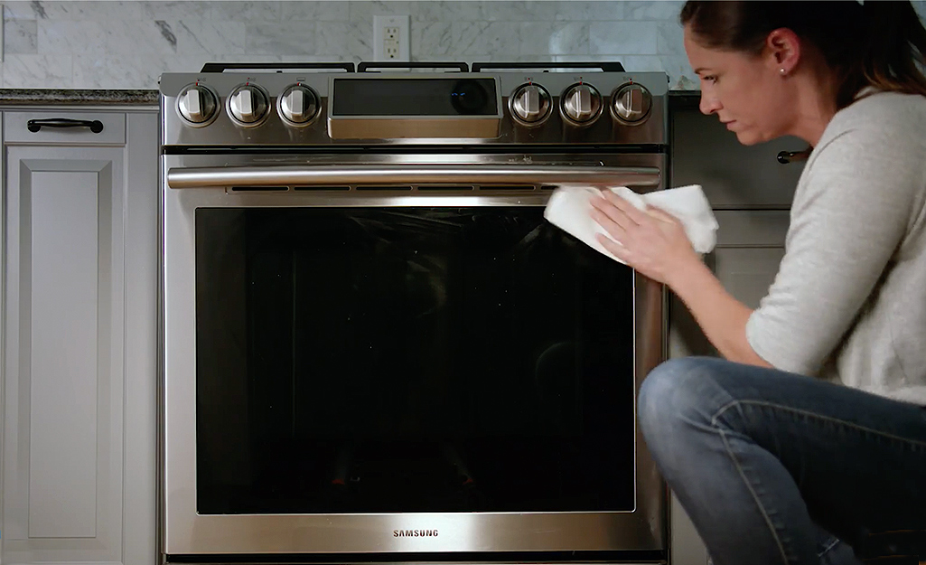 Someone cleaning an oven door.