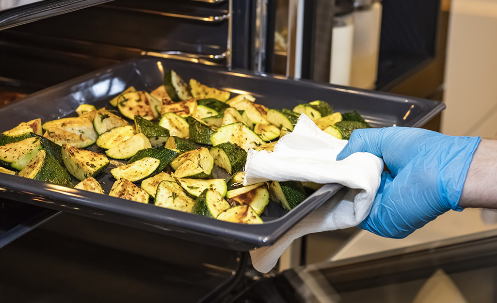 Someone pulling a pan of roasted vegetables from oven.