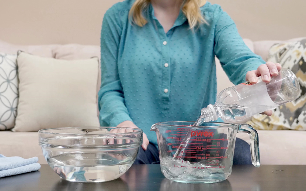 A person mixing a solution into a glass measuring bowl