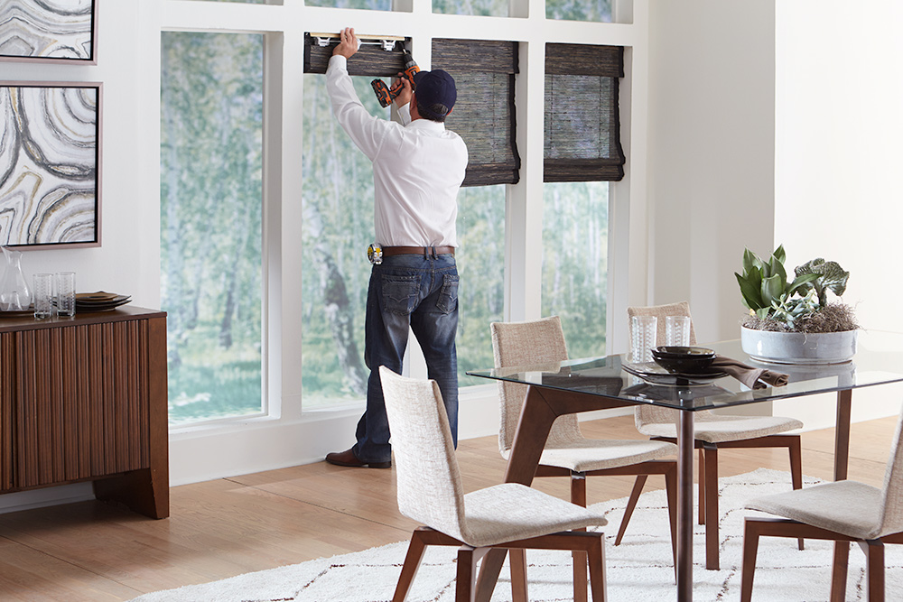 A person installing replacement blinds on a tall window